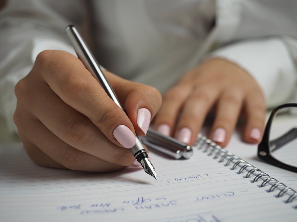 A detailed image of handwriting in a notebook with a fountain pen and glasses preparing to raise performance concerns