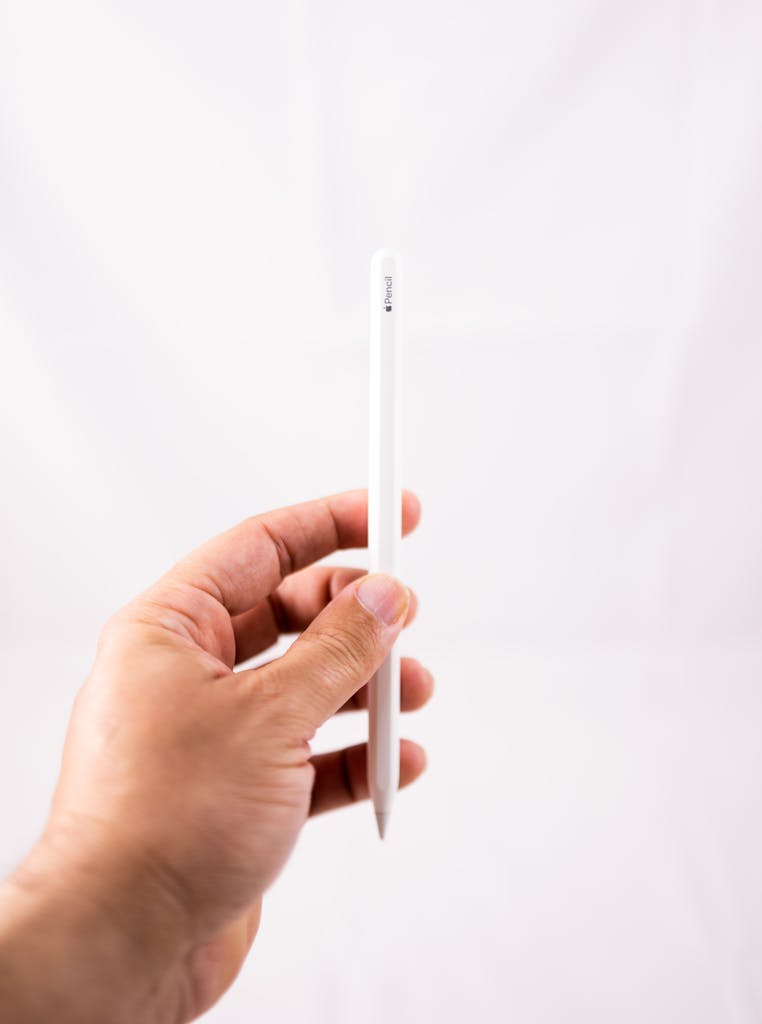 Close-up of a hand holding a stylus pen vertically against a white background.