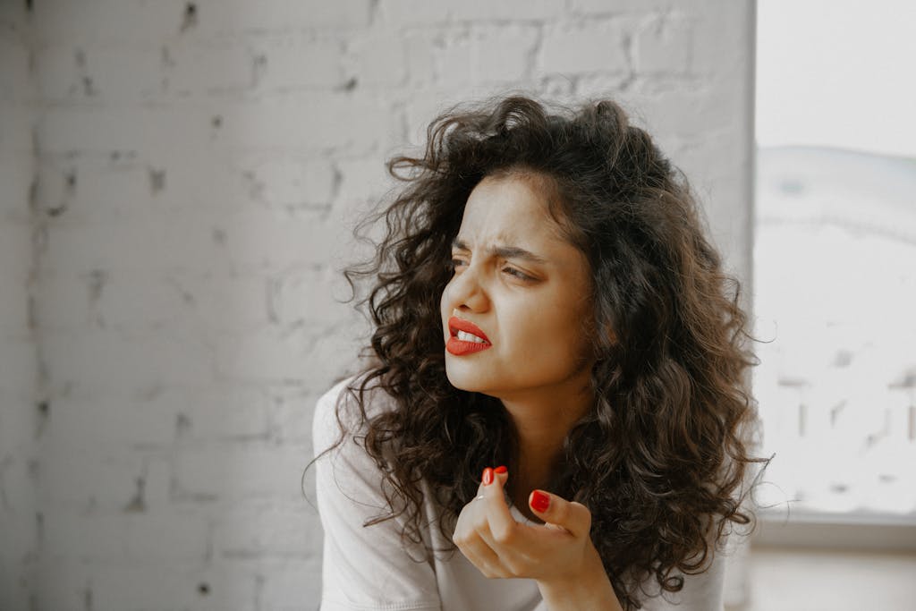 A brunette woman showing an expression of uncertainty against a brick wall about leadership lessons