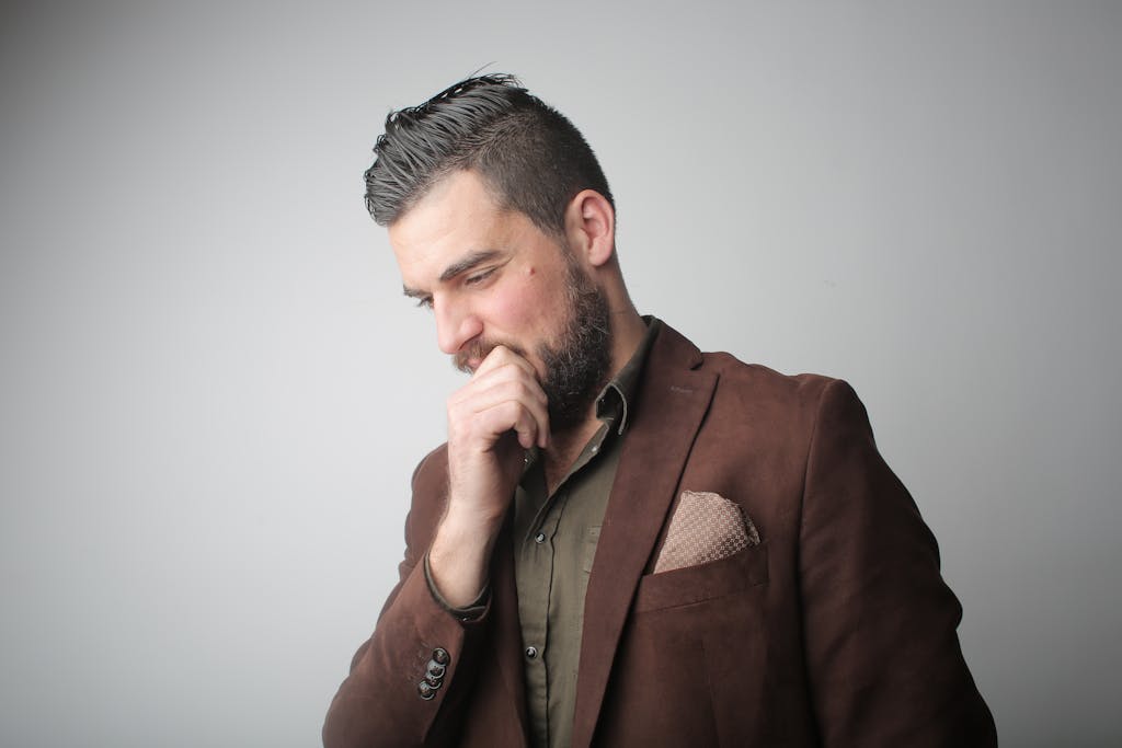 Thoughtful bearded manager in brown suit contemplating problem solving.